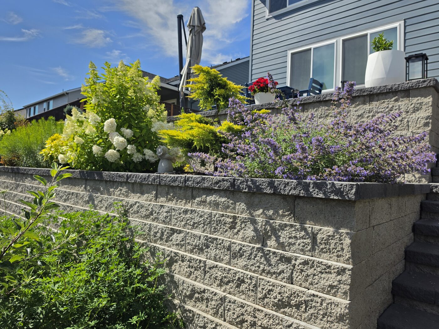Terraced retaining wall with established flowering plants beside a Ridgefield outdoor living space